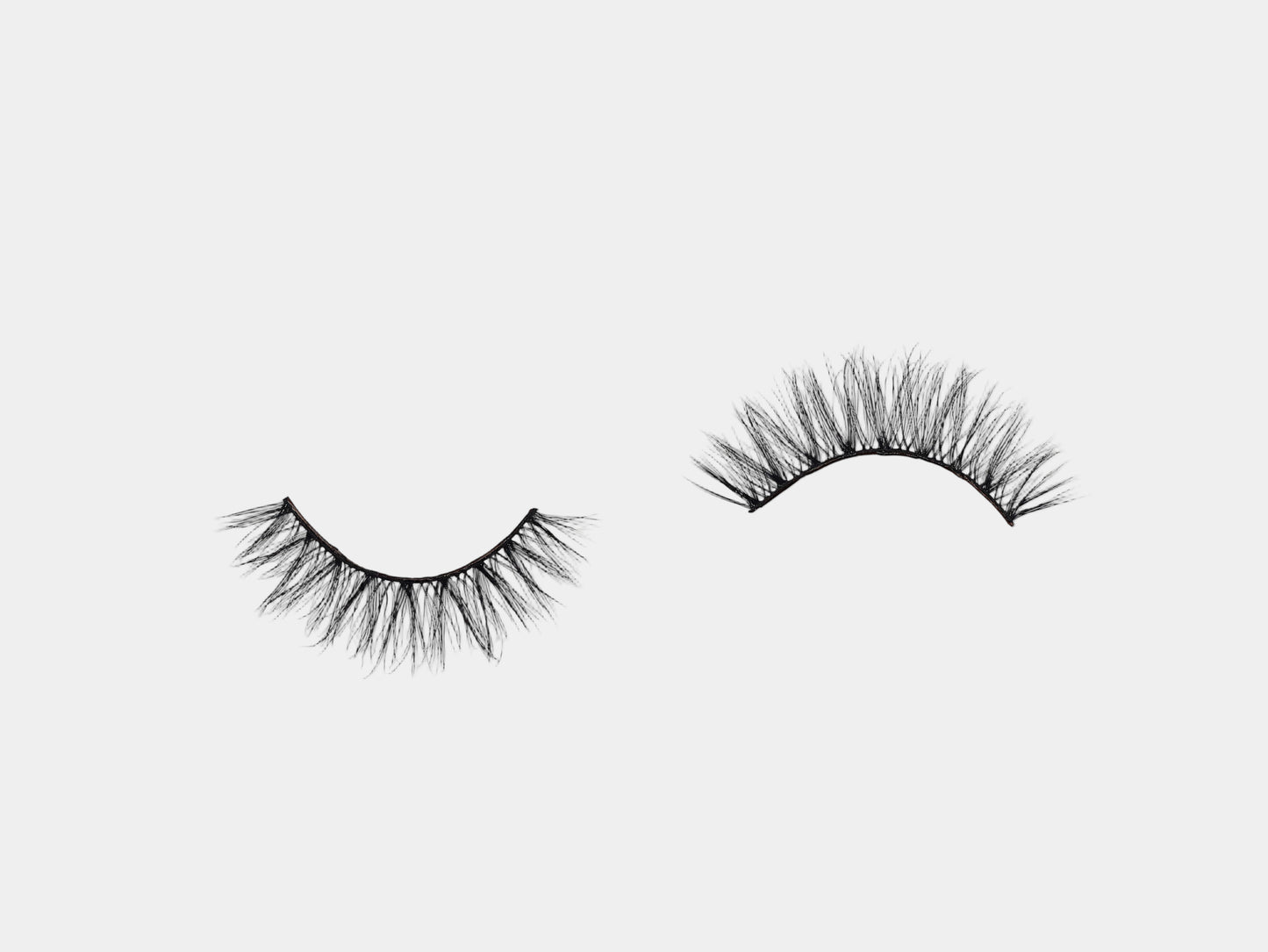 Doll Eye Day & Night Duo day lashes arranged in opposite directions on a light gray background