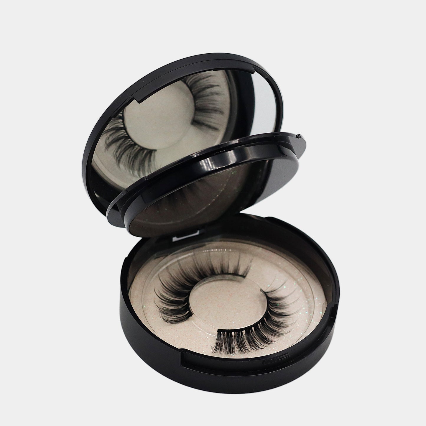Mirrored strip lash compact open showing bottom tray with lashes