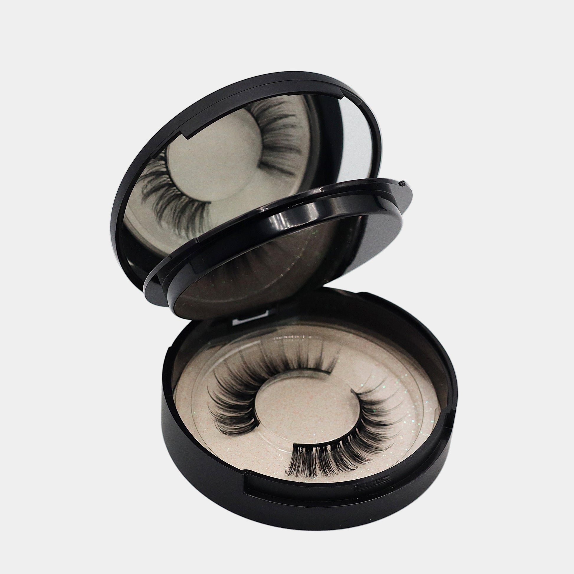 Mirrored strip lash compact open showing bottom tray with lashes
