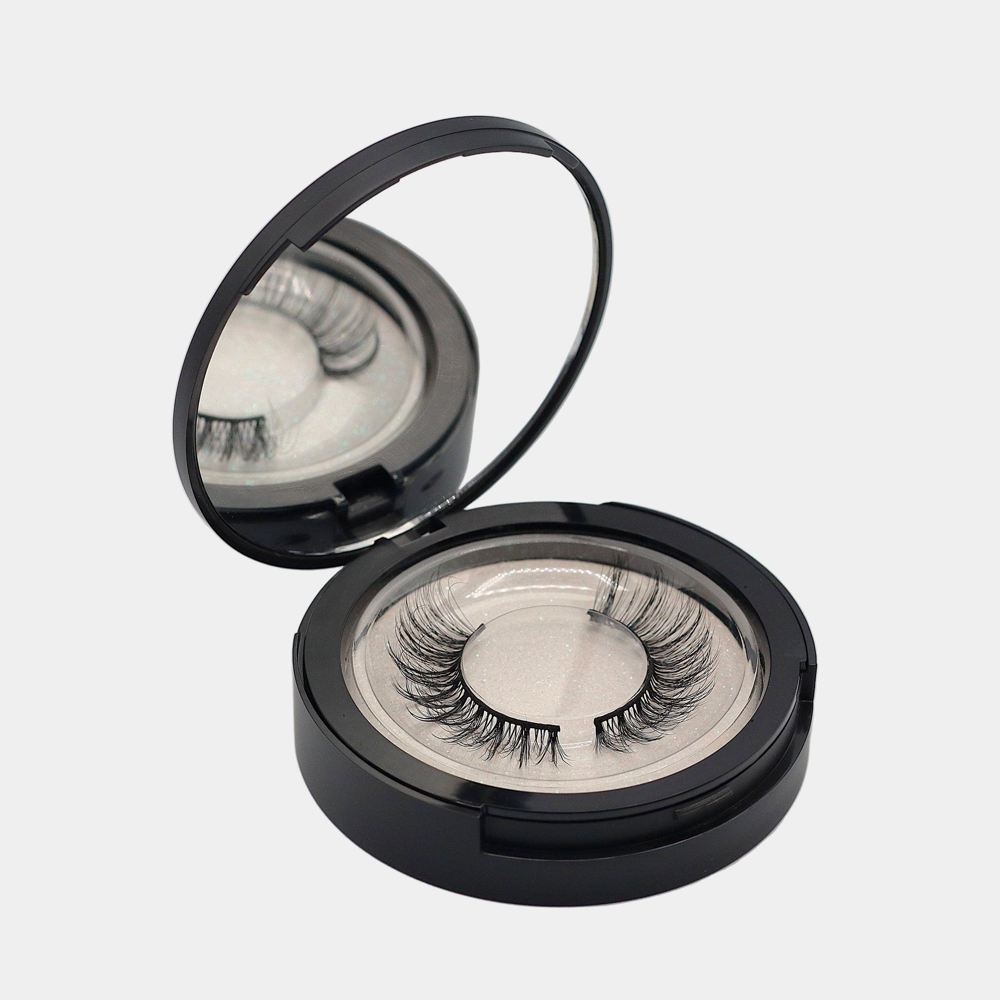 Mirrored strip lash compact open showing top tray with lashes
