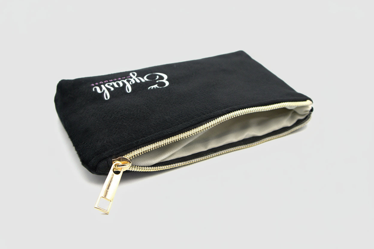Open black travel pouch showing inside material with gold zipper on a light gray background