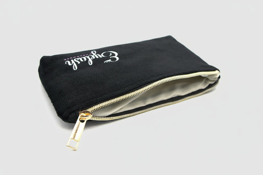 Open black travel pouch showing inside material with gold zipper on a light gray background